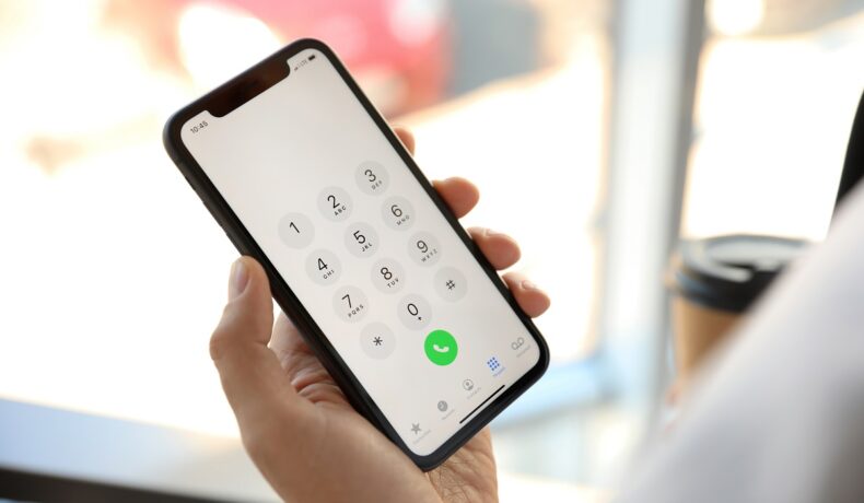 Iphone 11, cu ecran keypad pe alb, cifre gri, buton verde de apelare, ținut în mână. „Codurile secrete” iPhone sunt introduse pe keypad