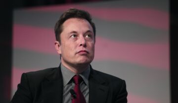 Elon Musk, la conferința Automotive News World Congress, în anul 2015. E pe scenă, îmbrăcat în costum negru, cămașă gri, cravată roșu cu negru. Elon Musk a dezvăluit opiniile sale despre natalitate