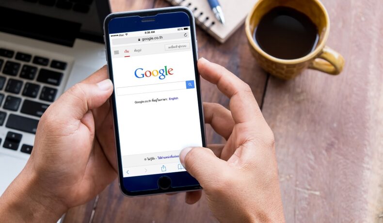 Motorul de căutare Google pe ecranul unui telefon ținut în mână de utilizator. Google a închis recent un alt serviciu