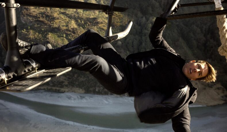 Tom Cruise, în filmul Mission Impossible, îmbrăcat în negru, în timp ce stă atârnat de un elicopter. Tom Cruise va filma în spațiu după următorul film din serie