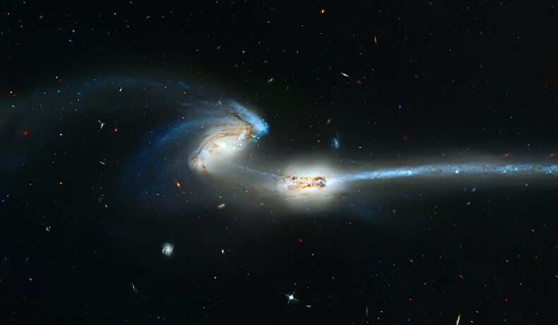 O coliziune între două galaxii albastre, pe fundal negru. Telescopul Hubble a surprins o coliziune între galaxii similară
