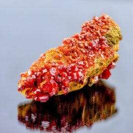 Mineral de vanadinit, roșu și portocaliu, pe fundal gri. Oxidul de vanadinit e compusul care are memorie