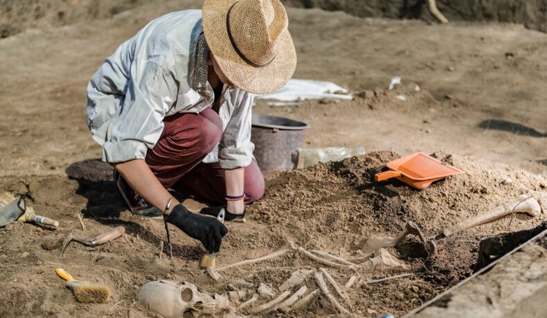 Arheolog care examinează un schelet în mormânt. Experții au dezvăluit cum arăta un „vampir” din secolul 18
