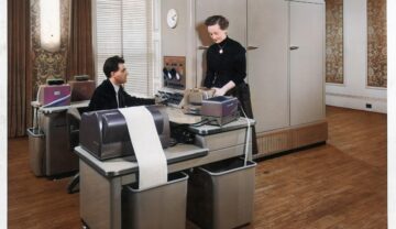 Bărbat care stă la un birou bechi, 1950, cu secretara și claculator în spatele, similar cun un calculator „legendar” ce a fost descoperit într-un beci
