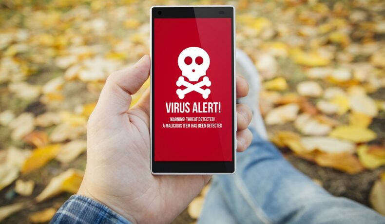 Utilizator care are în mână un telefon, cu un ecran roșu cu un virus. „Cele mai periculoase aplicații” se pot găsi și în Google Play Store