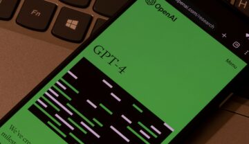 GPT-4, care e de sute de ori mai puternic decât ChatGPT, pe ecranul verde al unui telefon, lângă o tastatură de laptop