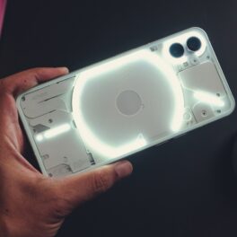 Telefon Nothing Phone (1), considerat „rivalul iPhone-ului”, cu luminile pe spate aprinse, ținut în mână de un utilizator