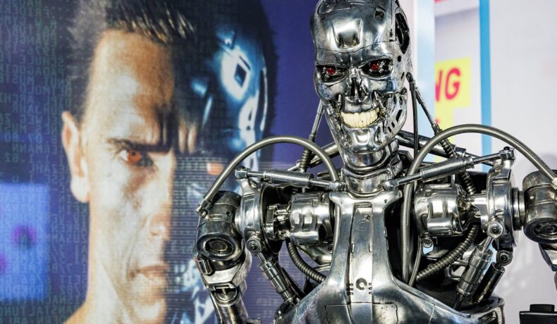Robot Terminator, cu fața lui Arnold Schwarzenegger pe fundal, pentru a ilustra cum experții au creat un material Terminator