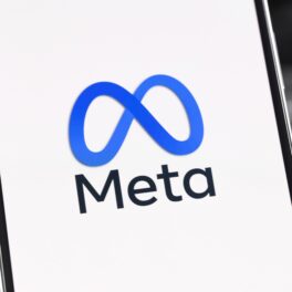 Logo-ul Meta pe ecranul alb al unui telefon mobil, cu un laptop pe fundal, pentru a ilustra cum Meta lansează un model de inteligență artificială