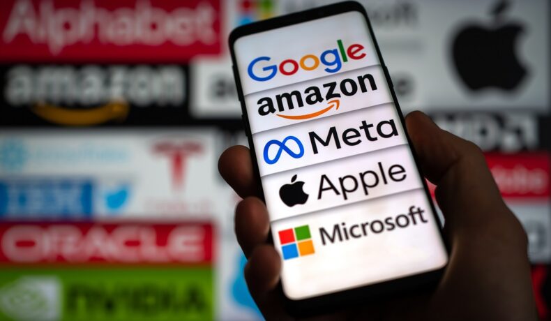 Utilizator care are în mână un telefon care are pe ecran simbolurile pentru Google, Amazon, Meta, Apple și Microsoft, care au făcut parte din „Cei 7 Magnifici”