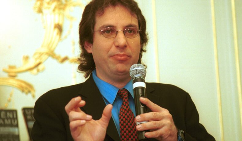 Kevin Mitnick, „cel mai căutat hacker din lume”, în 2003, după ce a ieșit din închisoare, cu un microfon în mână, îmbrăcat în costum negru