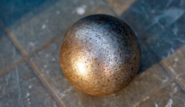 Sferă de metal, ruginită, pe fundal gri, similară cu primele obiecte „extraterestre” de pe Pământ