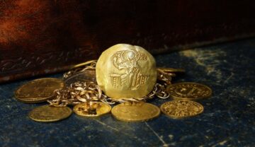 Monede de aur cu un lanț, pe fundal de lemn închis, pentru a ilustra cum un bărbat a făcut „descoperirea secolului”
