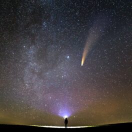 Fotograf care se uită la cerul înstelat, cu o cometă deasupra, similară cu un eveniment astronomic unic care va avea loc în septembrie 2023