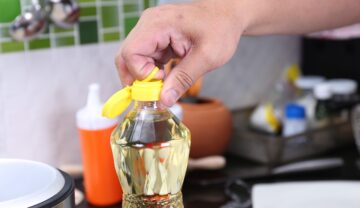 Bărbat care deschide o sticlă de ulei și trage de dopul cu inel, care folosește la o funcție ce a uimit internauții, pe fundal de bucătărie
