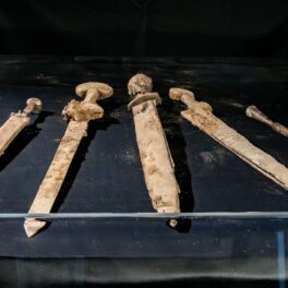 Săbii romane descoperite în Israel, în nuanțe de bej, pe fundal negru, expuse sub sticlă, 2023