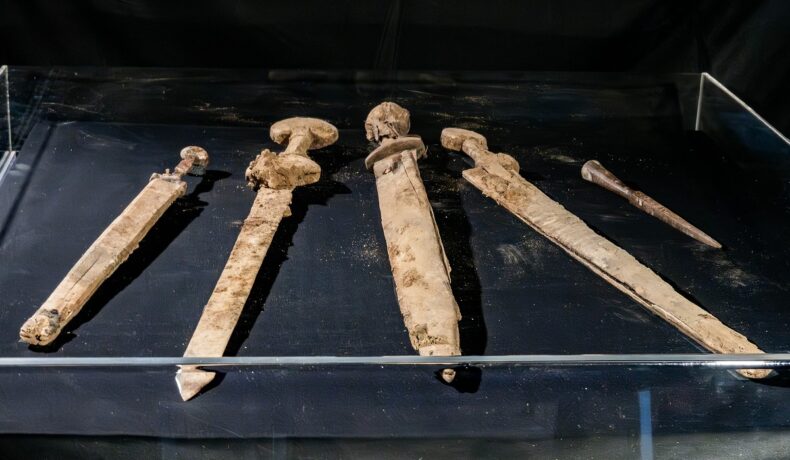 Săbii romane descoperite în Israel, în nuanțe de bej, pe fundal negru, expuse sub sticlă, 2023